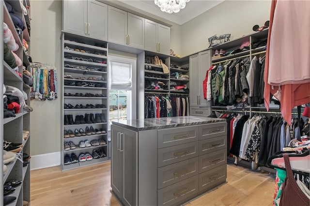 spacious closet with light wood finished floors and a chandelier