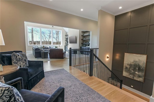 living room with light wood-type flooring, a decorative wall, and recessed lighting