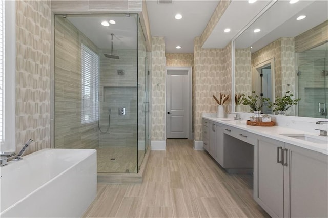 bathroom with double vanity, a freestanding tub, a stall shower, and a sink