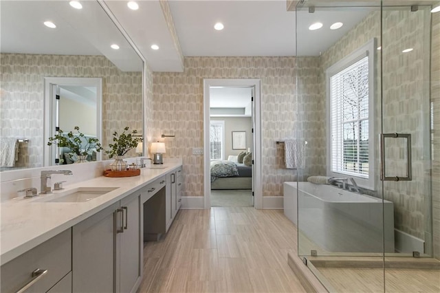 bathroom featuring wallpapered walls, plenty of natural light, a sink, and a shower stall