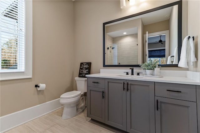 full bathroom with toilet, a stall shower, baseboards, and vanity