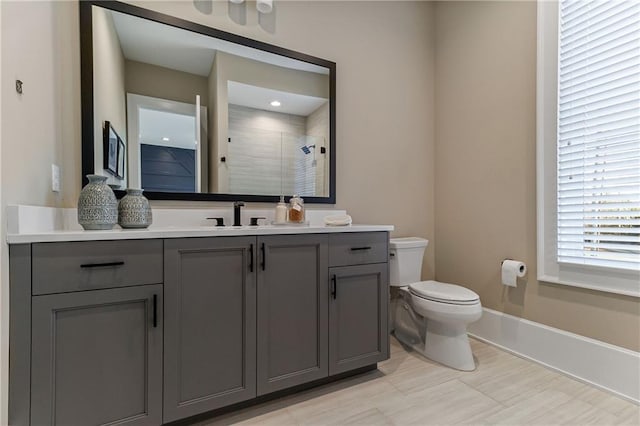 full bath featuring toilet, a stall shower, baseboards, and vanity