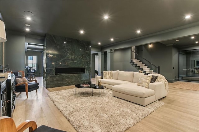 living room with recessed lighting, wood finished floors, decorative columns, and a premium fireplace