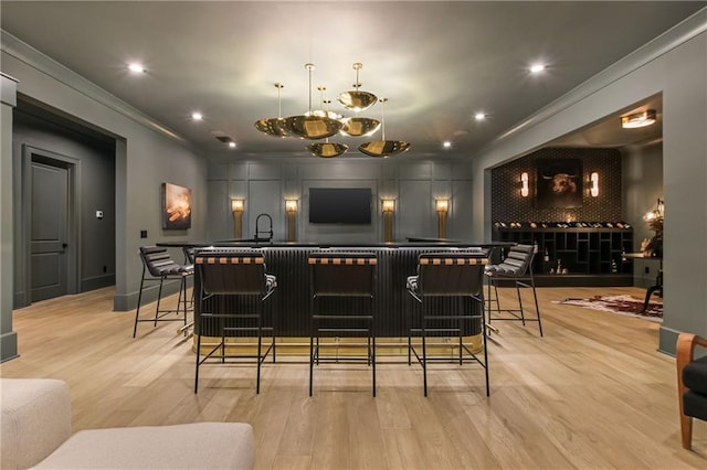 bar with light wood-type flooring, crown molding, decorative backsplash, and indoor wet bar