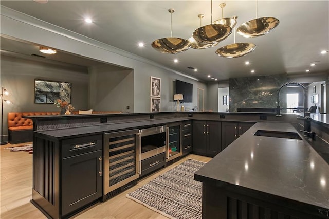 kitchen featuring beverage cooler, dark countertops, light wood-style flooring, crown molding, and recessed lighting