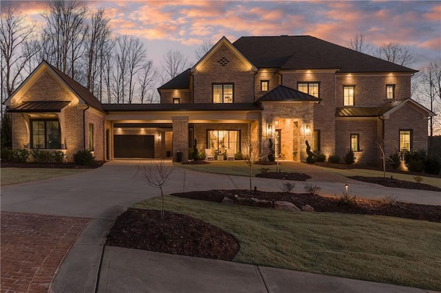 view of front of property with a yard, driveway, brick siding, and a standing seam roof