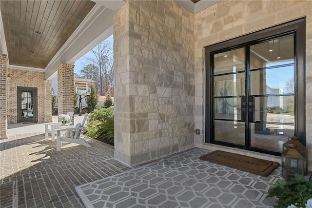 doorway to property featuring stone siding, a patio, and brick siding