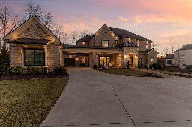 view of front of property featuring metal roof, brick siding, a yard, concrete driveway, and a standing seam roof