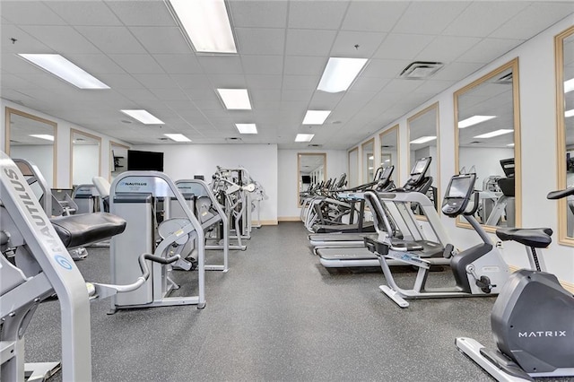 workout area with a paneled ceiling, visible vents, and baseboards