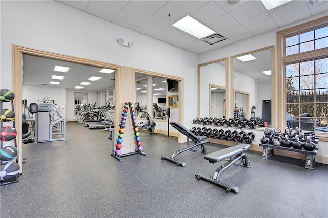 exercise room featuring a paneled ceiling, visible vents, and baseboards