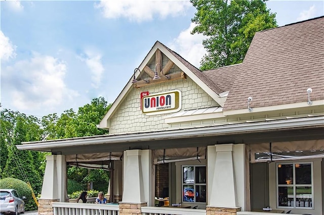 exterior space featuring covered porch and a shingled roof