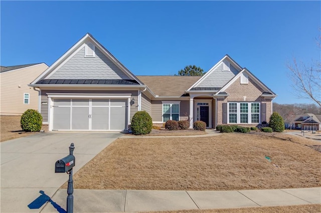 craftsman-style house with a garage, driveway, brick siding, and a standing seam roof