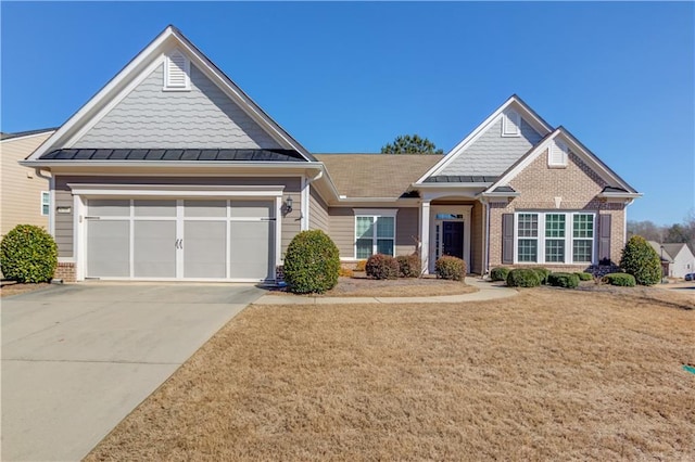 craftsman-style home featuring metal roof, an attached garage, brick siding, driveway, and a standing seam roof