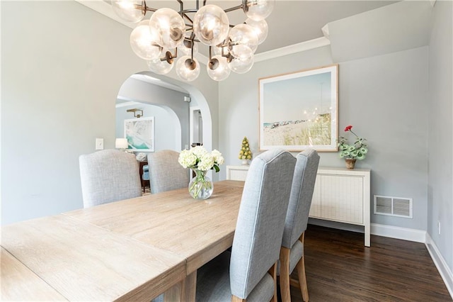dining room with a chandelier, arched walkways, wood finished floors, baseboards, and ornamental molding