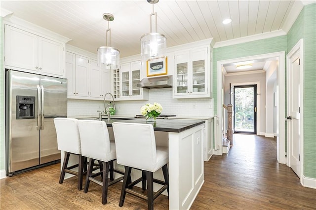 kitchen featuring stainless steel refrigerator with ice dispenser, crown molding, dark wood-style floors, under cabinet range hood, and a sink