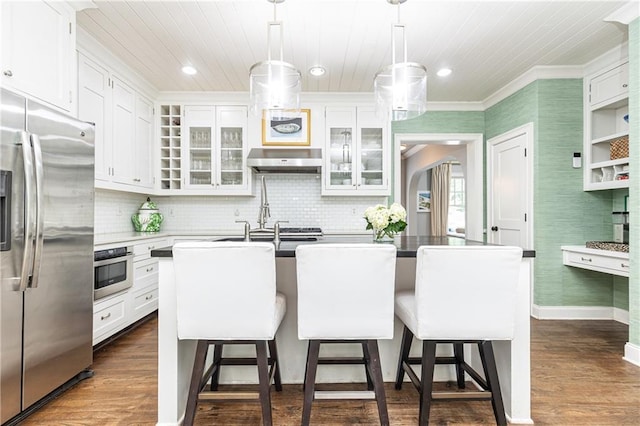 kitchen with appliances with stainless steel finishes, a breakfast bar, white cabinetry, under cabinet range hood, and recessed lighting