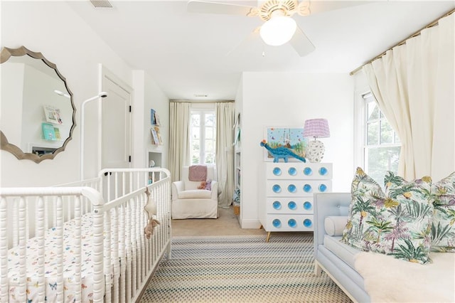 bedroom with light colored carpet, multiple windows, and a ceiling fan