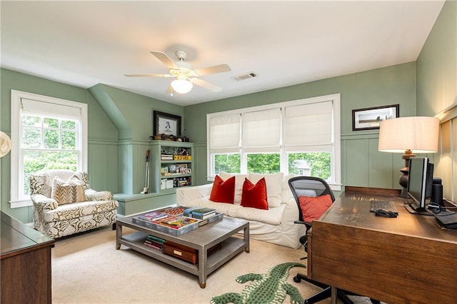 living area featuring a desk, ceiling fan, and a decorative wall
