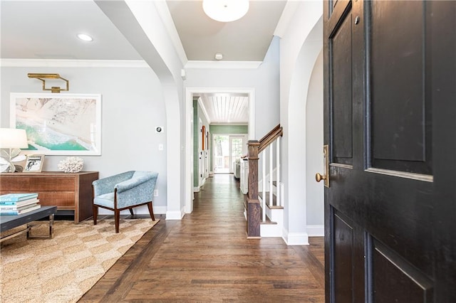 entrance foyer with arched walkways, baseboards, ornamental molding, dark wood finished floors, and stairway
