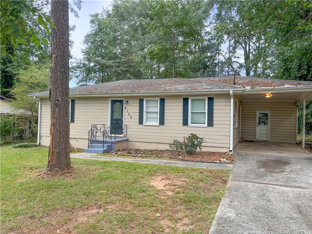 single story home featuring a front lawn and a carport