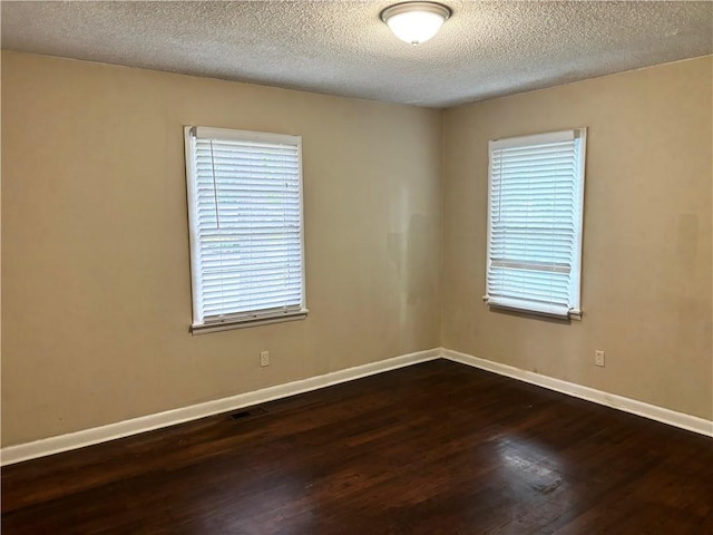 unfurnished room with a textured ceiling and dark wood-type flooring