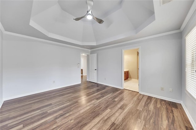 unfurnished bedroom with crown molding, hardwood / wood-style floors, a tray ceiling, and ensuite bath