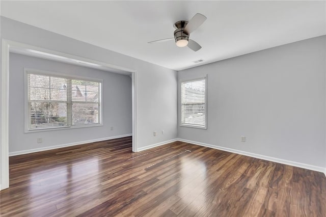 empty room featuring ceiling fan, a wealth of natural light, and dark hardwood / wood-style flooring