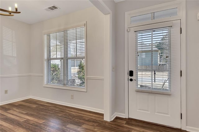 doorway to outside with plenty of natural light, dark hardwood / wood-style floors, and a chandelier