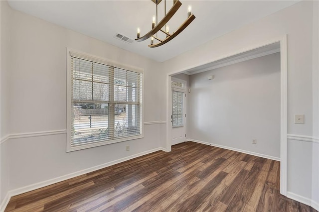 spare room with dark hardwood / wood-style flooring and a chandelier