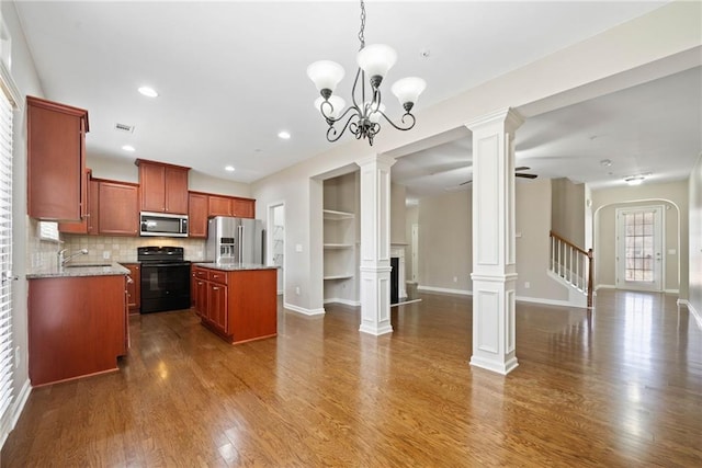 kitchen featuring decorative light fixtures, appliances with stainless steel finishes, dark hardwood / wood-style floors, a kitchen island, and decorative columns