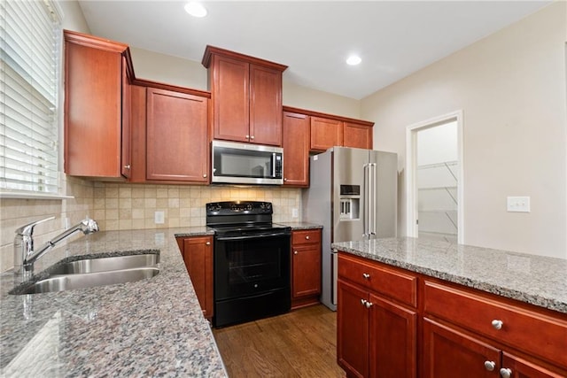 kitchen with sink, light stone counters, appliances with stainless steel finishes, dark hardwood / wood-style flooring, and decorative backsplash