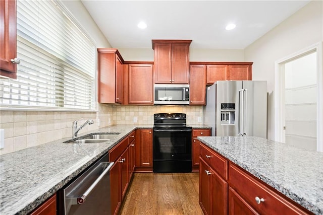 kitchen featuring stainless steel appliances, light stone countertops, sink, and decorative backsplash