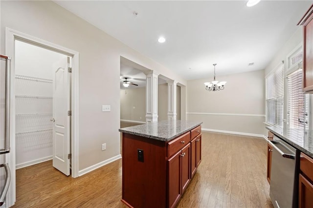 kitchen with hanging light fixtures, decorative columns, a center island, stainless steel dishwasher, and dark stone counters