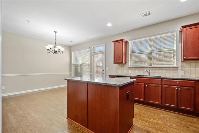 kitchen with sink, a center island, pendant lighting, light hardwood / wood-style floors, and decorative backsplash