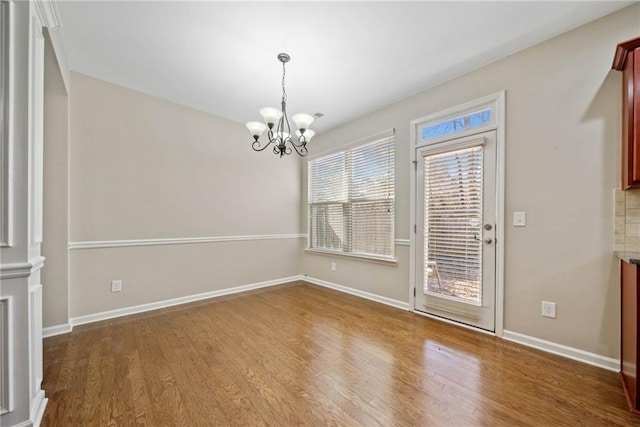 unfurnished dining area featuring hardwood / wood-style flooring and a notable chandelier