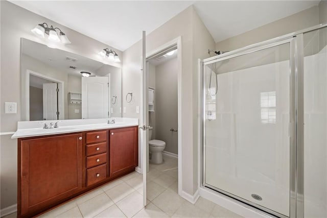 bathroom with a shower with door, vanity, tile patterned floors, and toilet