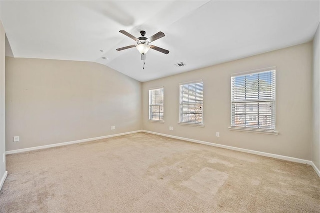 carpeted empty room featuring a wealth of natural light, vaulted ceiling, and ceiling fan