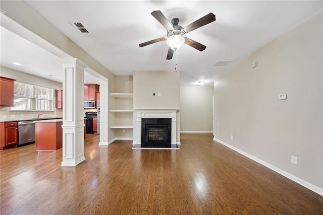 unfurnished living room with dark hardwood / wood-style flooring, sink, decorative columns, and ceiling fan