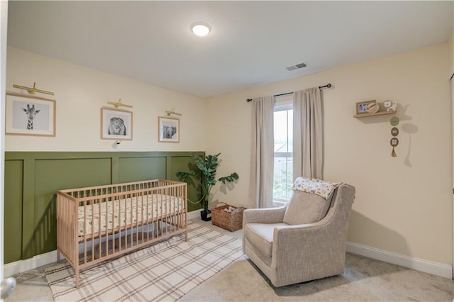 bedroom featuring a nursery area, baseboards, a decorative wall, and visible vents