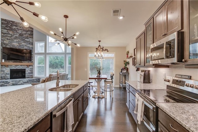 kitchen featuring a sink, glass insert cabinets, stainless steel appliances, a notable chandelier, and visible vents