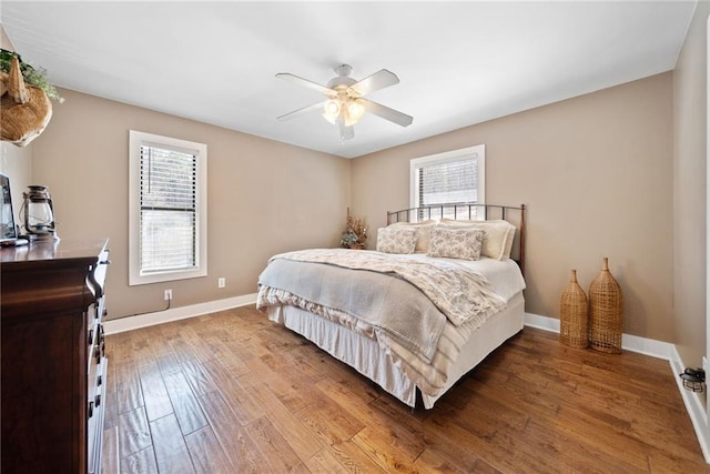 bedroom featuring wood finished floors, baseboards, and multiple windows