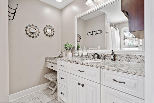 full bath with vanity, tile patterned flooring, and baseboards