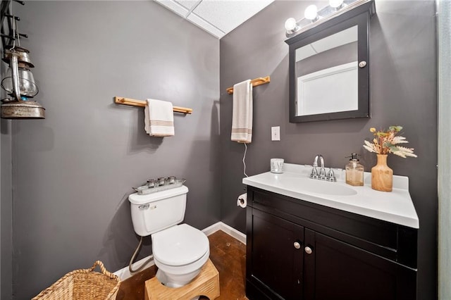 half bathroom with baseboards, toilet, and vanity