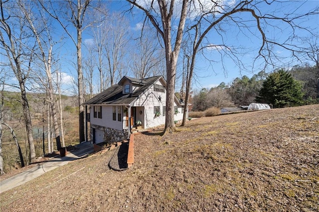 view of property exterior with a garage, stone siding, and concrete driveway