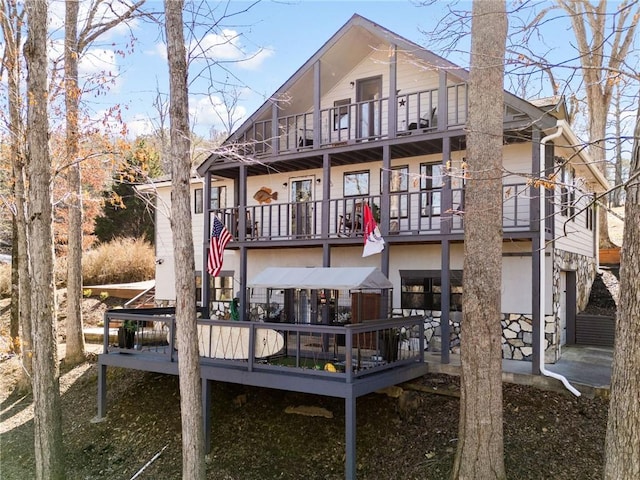 rear view of house featuring stone siding and a balcony