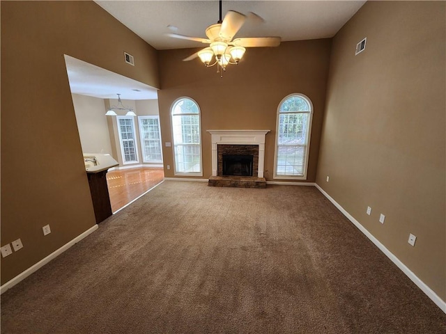 unfurnished living room with carpet, a fireplace, visible vents, and baseboards