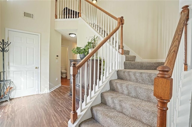 stairway featuring wood-type flooring and a high ceiling