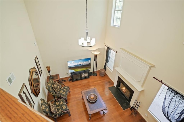 living room featuring an inviting chandelier, hardwood / wood-style floors, and a towering ceiling