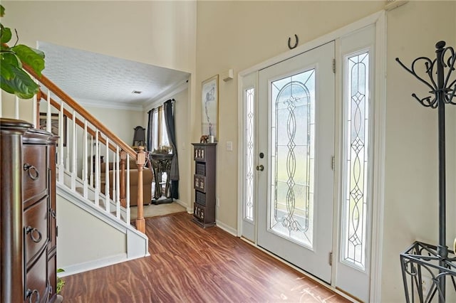 foyer entrance with crown molding, hardwood / wood-style flooring, a textured ceiling, and a wealth of natural light