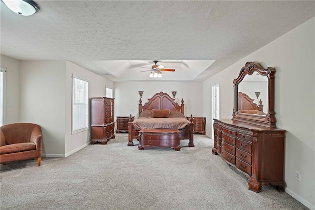 carpeted bedroom with ceiling fan, a textured ceiling, and a tray ceiling